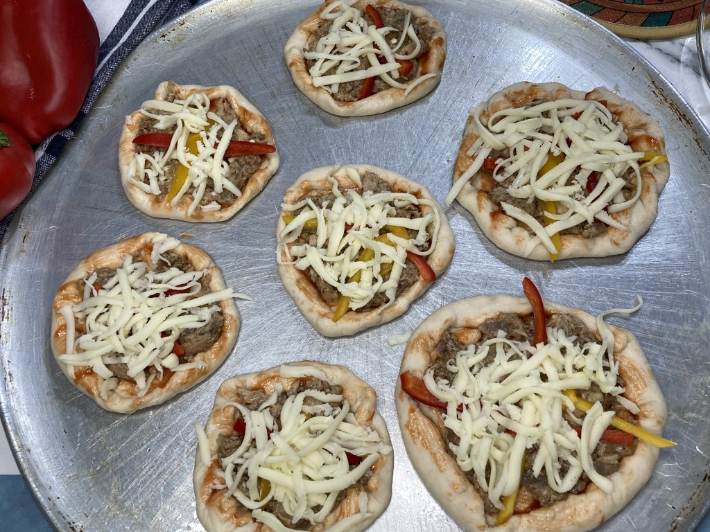spread mozzarella cheese on mini pizza
